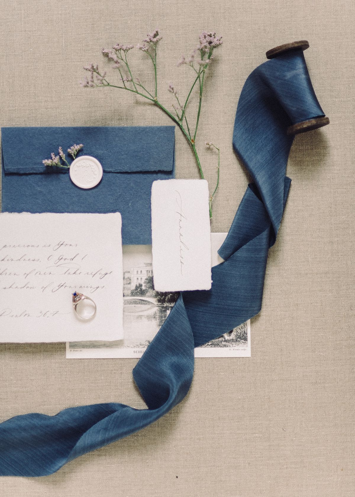 Wedding invitation with a blue envelope, ribbon and delicate floral details